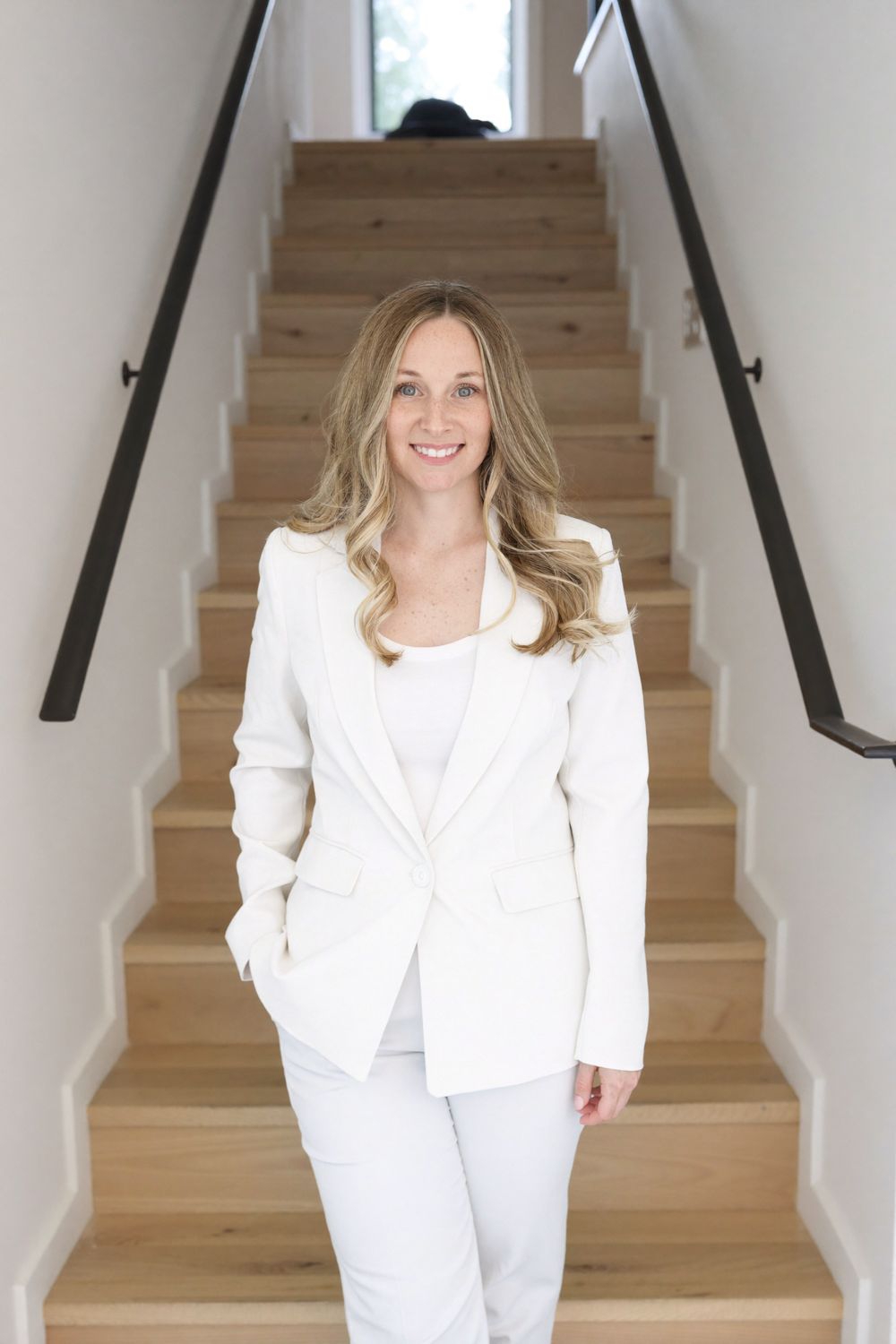 Desiree Lofredo standing on a staircase in a white suit
